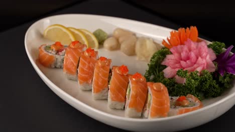 A beautifully arranged platter of fresh salmon sushi rolls topped with fish roe. 아름답게 담긴 플래터에 신선한 연어 스시 롤과 날치알이 조화를 이룸.