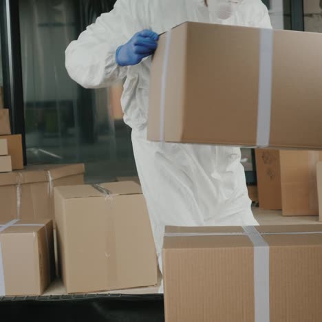 trabajador con ropa protectora carga cajas de medicamentos en el maletero del coche
