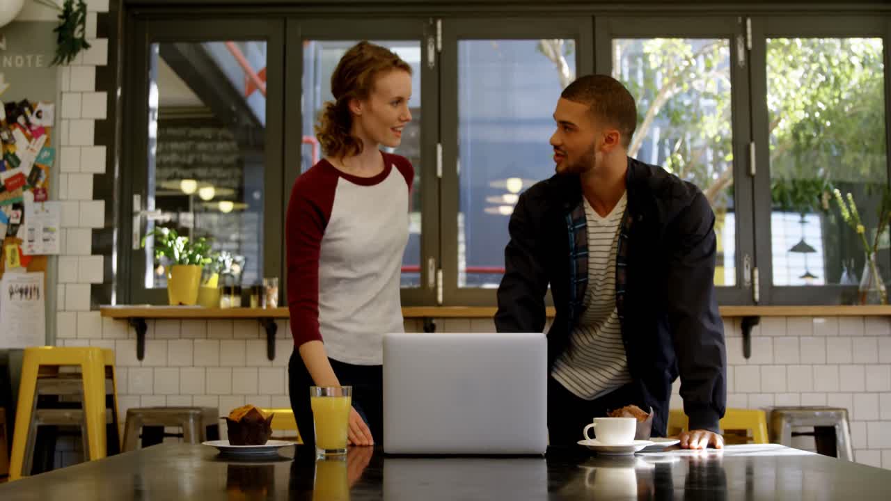 Man and woman executive discussing over a laptop in office cafeteria 4K 4k