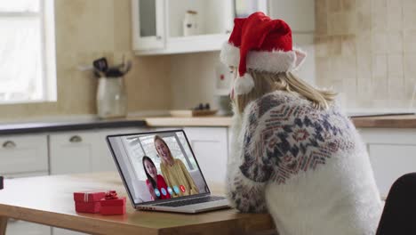 Caucasian-woman-wearing-santa-hat-using-laptop-on-video-chat-during-christmas-at-home