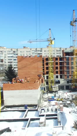 hoisting cranes and building activity. aerial view of crane and building construction site in winter season