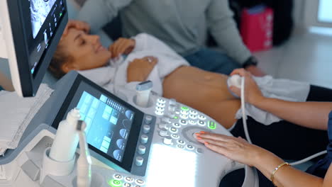medic performs ultrasound check up for pregnant lady. happy woman is smiling seeing her baby.