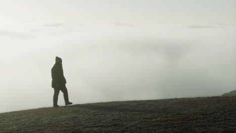 silhouette of a person walking on a foggy hill