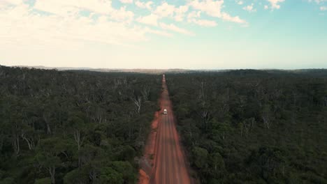 drone shot on of a van driving on a red dirt australian road from a distance in western australia