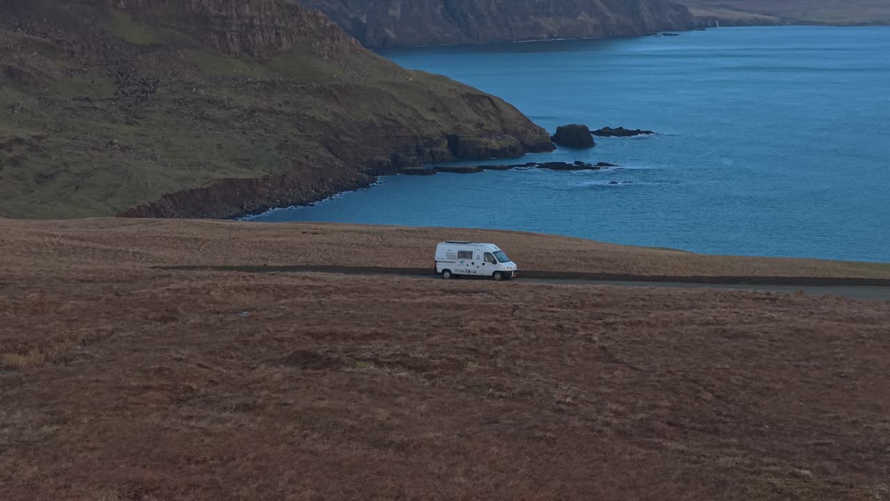 White campervan parked on a dramatic scottish coastline