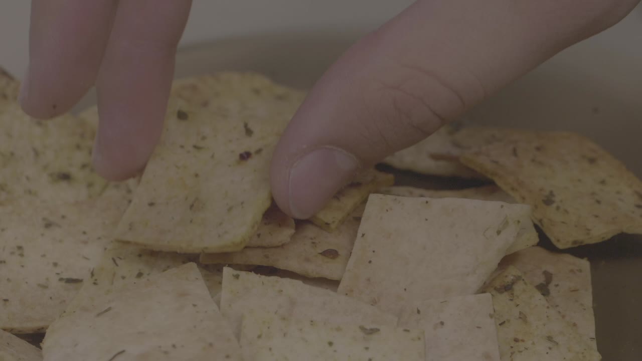 recogiendo a mano papas fritas de pita de un cuenco