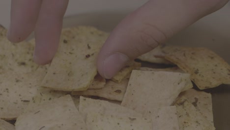 recogiendo a mano papas fritas de pita de un cuenco