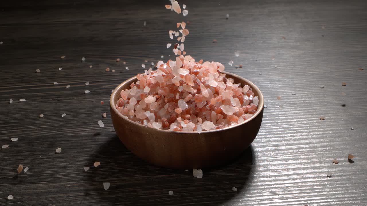 Himalayisk pink salt i super slow motion, naturlig mineralsk krydderi til sund madlavning og spa-koncepter. Super slow motion 1500 fps