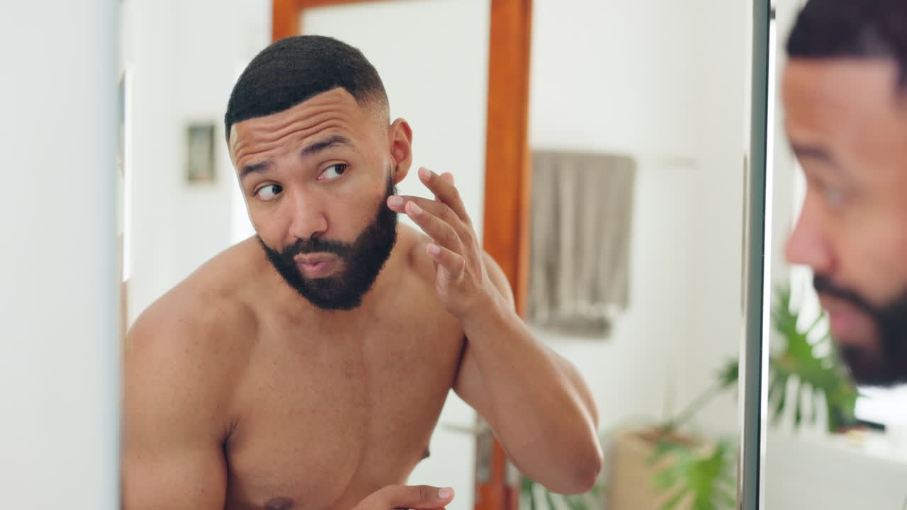 hombre aplicando loción delante del espejo del baño