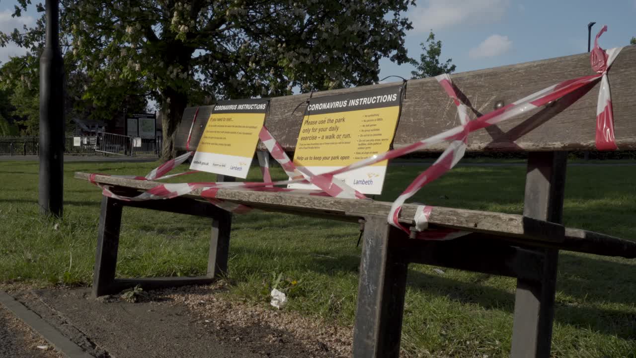 A caucasian woman jogging in a Park past a bench which has been closed due to Coronavirus lockdown in London