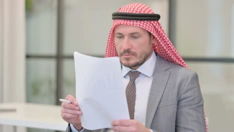 businessman reading reports while sitting in office