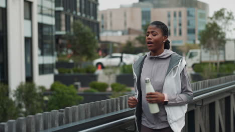 woman in athletic wear smiles and holds a water bottle