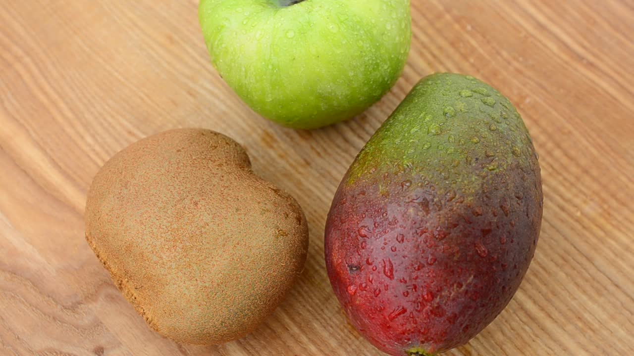 Frutta su un tagliere di legno. Mango, mela e kiwi. Riprese in movimento.