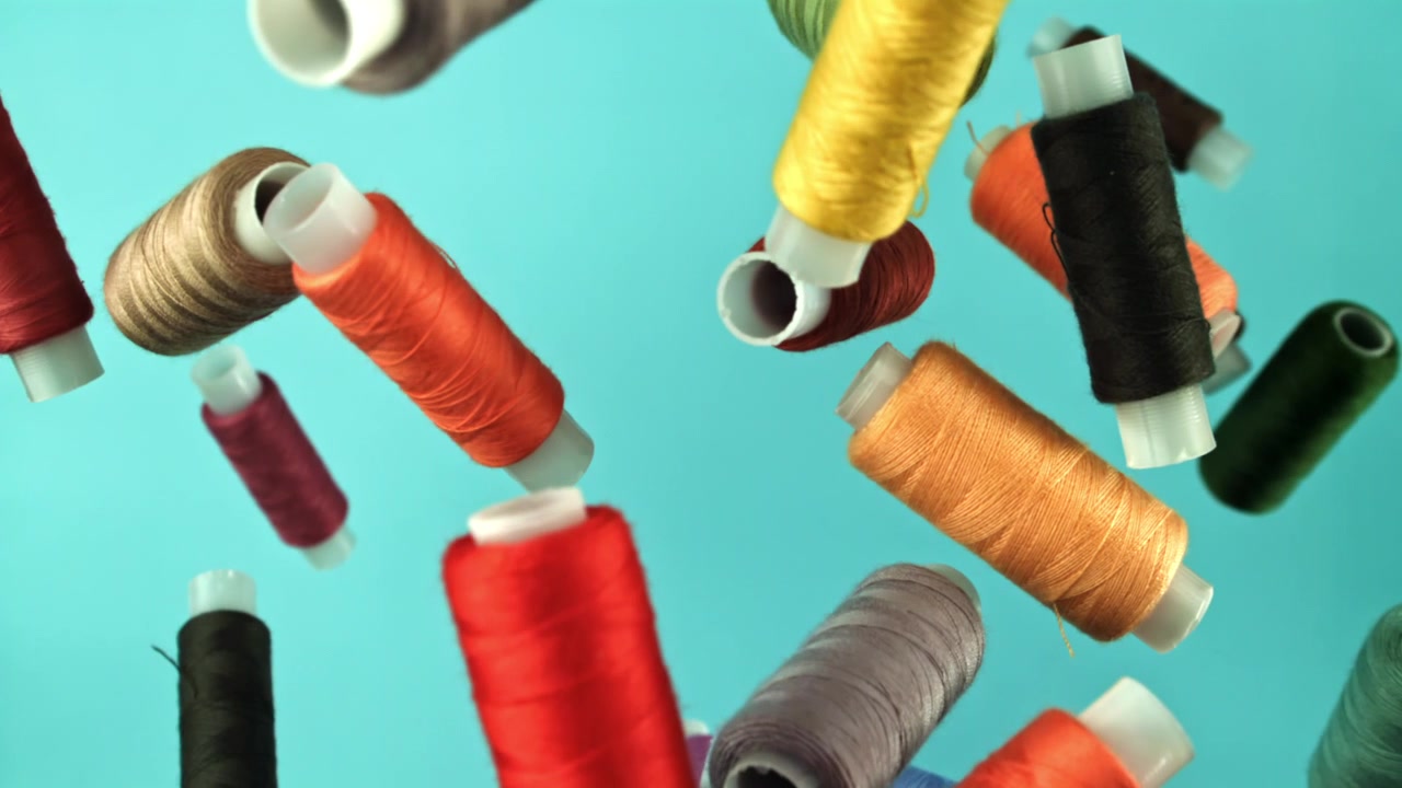 Colorful Sewing Thread Spools Falling in Slow Motion