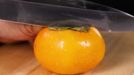 knife slicing through a ripe persimmon fruit