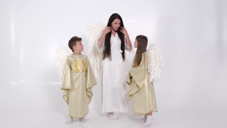 mom with children daughter and son dressed in angel costumes they dance on a white background mom with children daughter and son dressed in angel costumes they dance on a white background in the studio