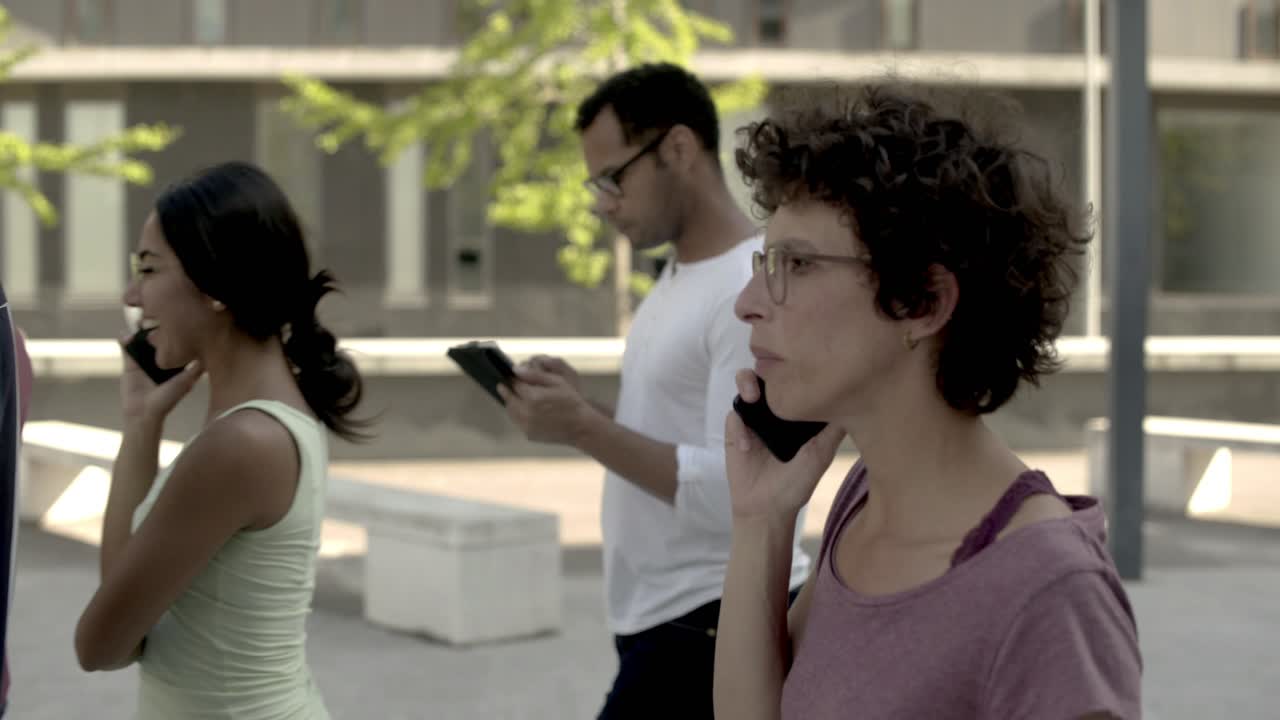 vista lateral de una mujer rizada sonriente hablando por teléfono en la multitud