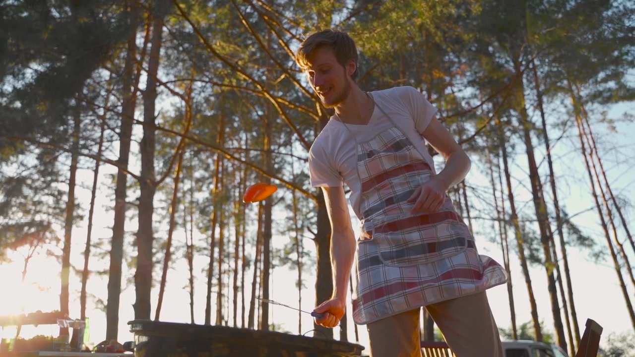 Young men cooking grilled food outdoors. Barbecue in the countryside. People enjoying a picnic in nature.