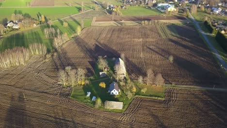 Ländliches-Konzept---Gepflügter-Schmutz-Auf-Ackerland-Mit-Bauernhaus