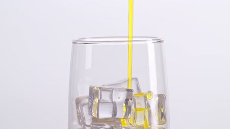 pouring orange juice into a glass with ice