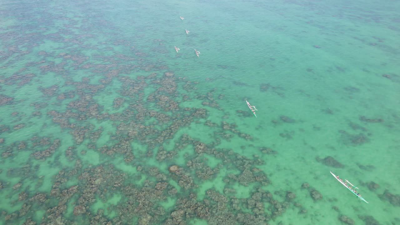 imágenes de drones a través del arrecife poco profundo lleno de agua cerca de la playa de lanakai oahu hawai con canoas hawaianas remando a través de la clara agua turquesa