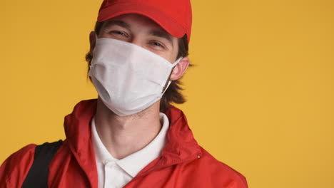 caucasian delivery man in front of camera on yellow background.