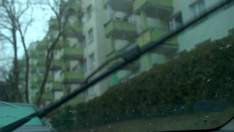 cámara lenta de la vista del día lluvioso durante las gotas de lluvia de los limpiaparabrisas del automóvil deslizándose hacia abajo dentro de un automóvil
