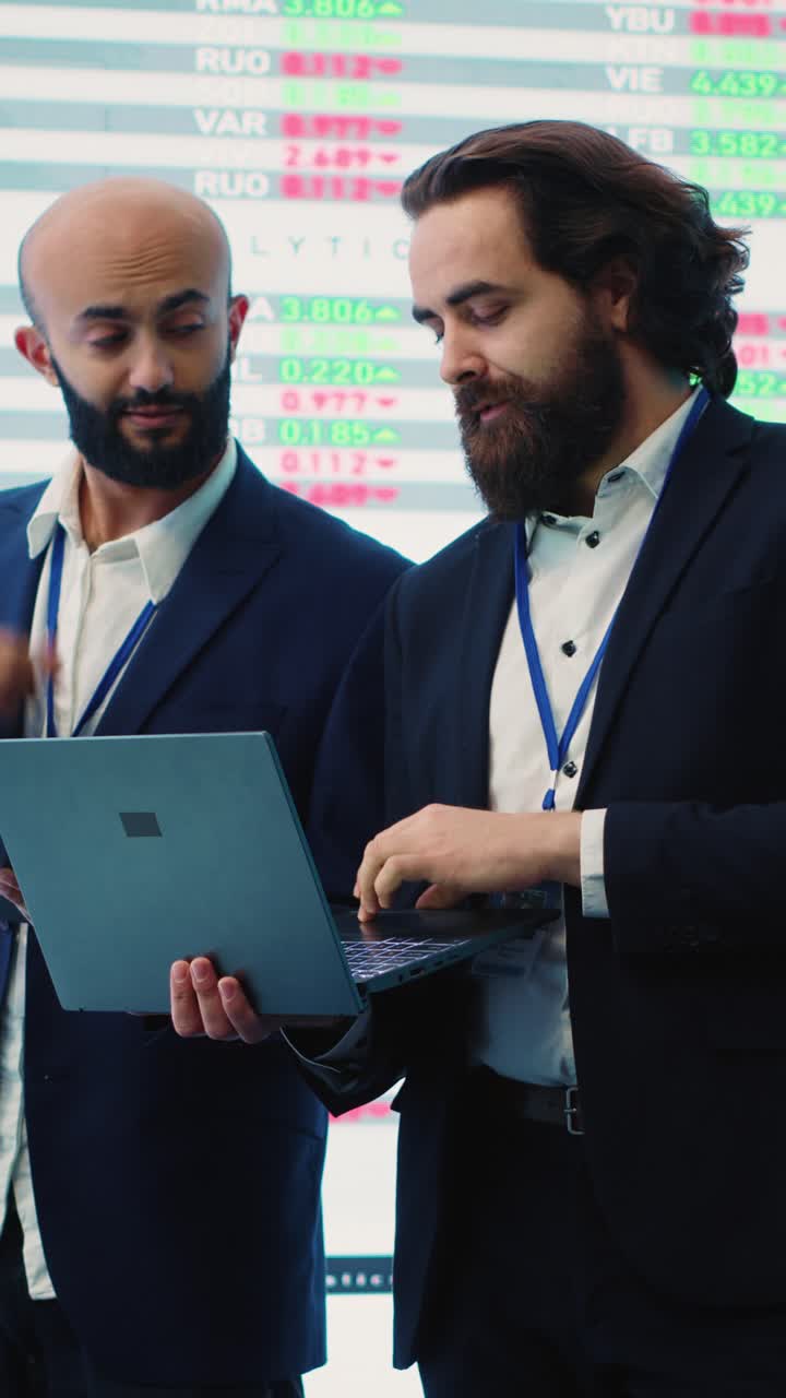 Dois empresários discutindo dados financeiros em um laptop em um escritório moderno