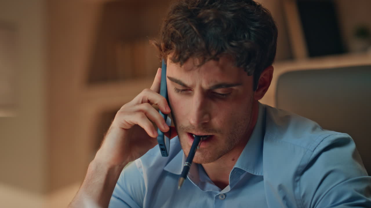 Business manager talking mobile phone in dark office holding pen close up.