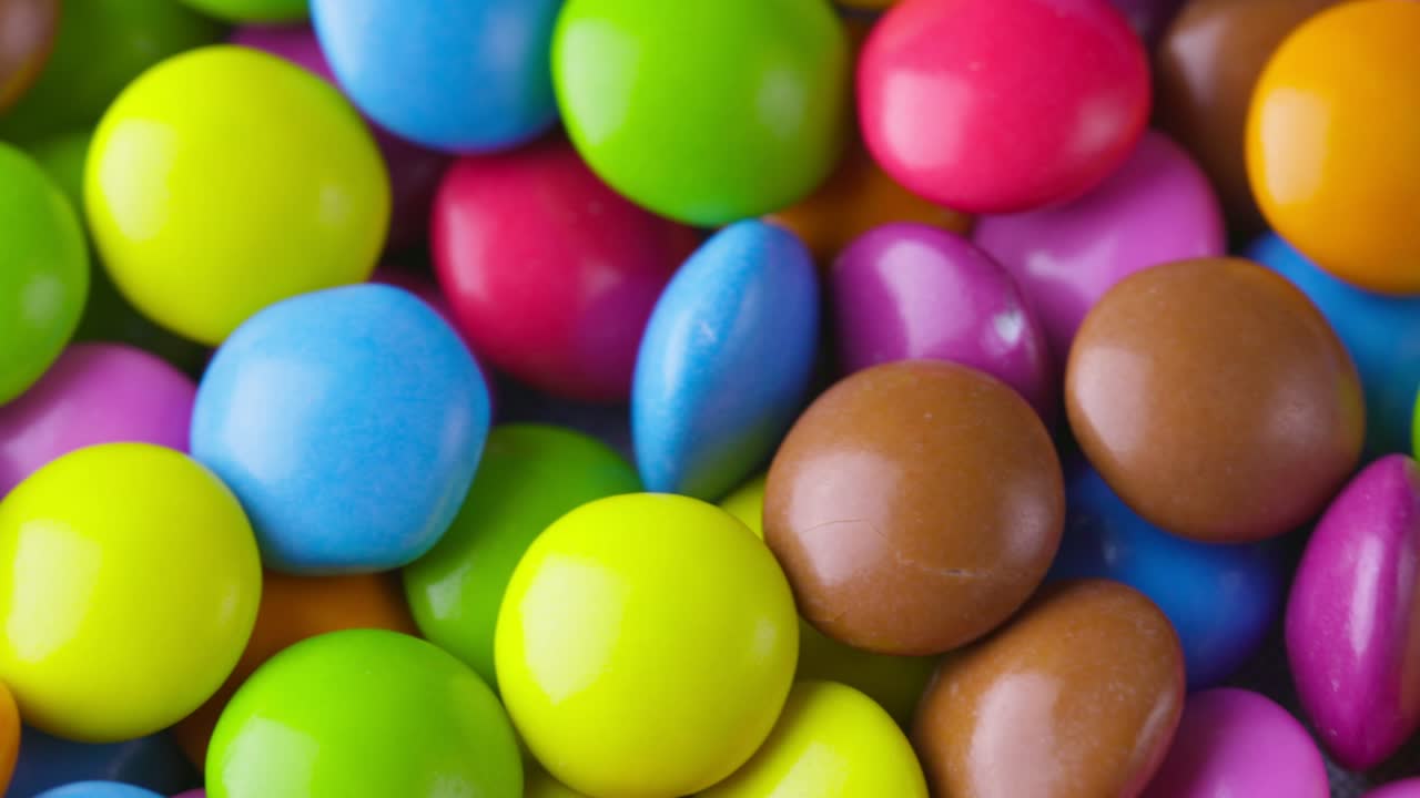 movimiento lento de primer plano de caramelos de chocolate redondos de colores, dragee. rotación y caída de caramellos de chocolate multicolores