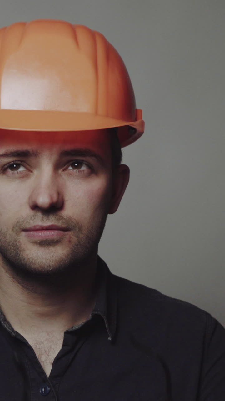 Portrait of young engineer with helmet. Young construction worker in hard hat on gray background