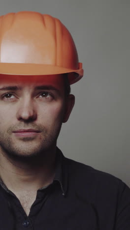 portrait of young engineer with helmet. young construction worker in hard hat on gray background