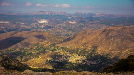 an aerial shot of clouds shadows moving across an urban landscape surrounded by mountains