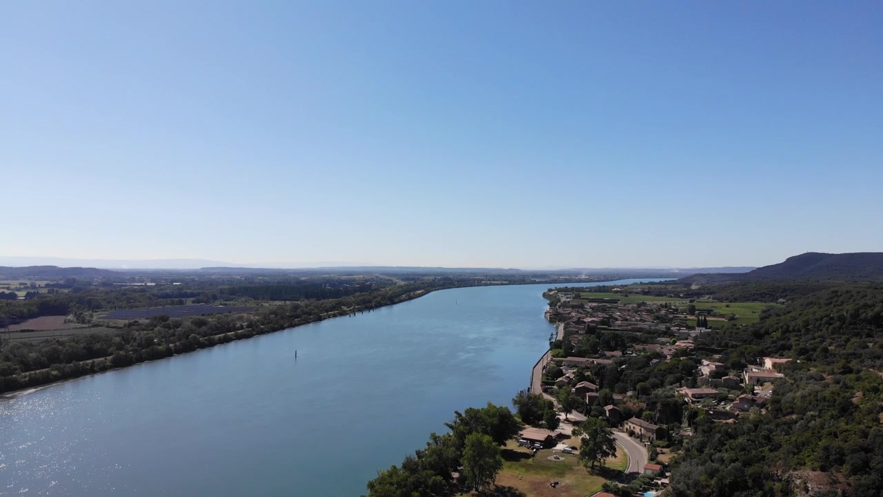 Veduta aerea del fiume Reno che scorre attraverso una pittoresca area rurale con un piccolo villaggio circondato da campi e paesaggio naturale all'orizzonte.