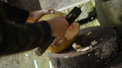 Close-Up-Shot-of-a-person-cutting-open-a-fresh-coconut-with-a-machete