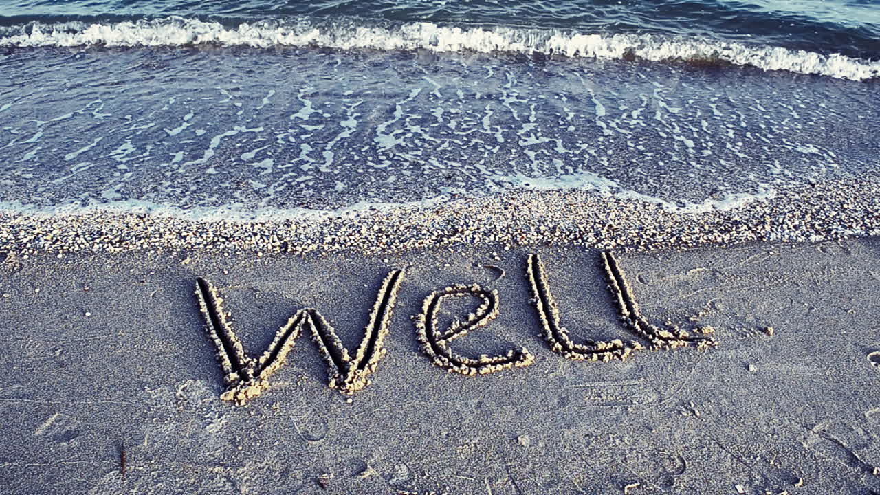 The inscription WELL on sand. Shooting on the beach