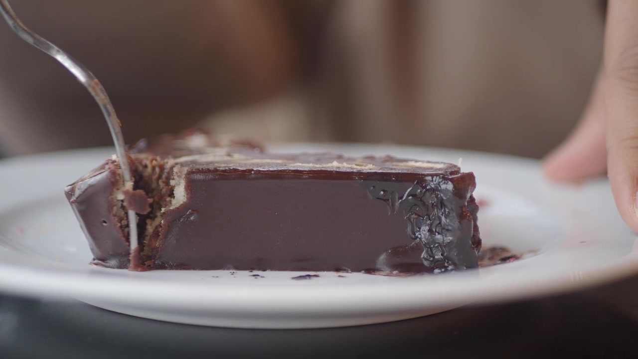 Persona che mangia una fetta di torta al cioccolato con una forchetta