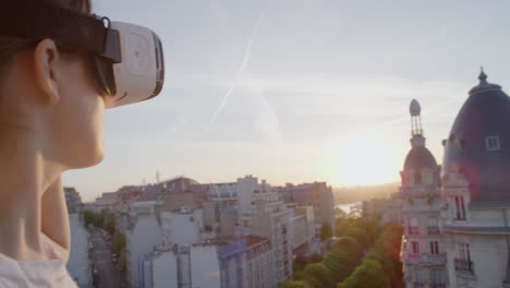 mujer usando auriculares de realidad virtual disfrutando explorando la experiencia del ciberespacio en línea en el balcón en el hermoso atardecer de parís de cerca