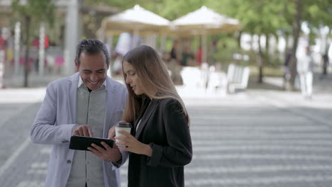 Happy-colleagues-using-tablet-pc-outdoor