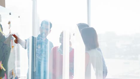 team of business executives discussing over glass board