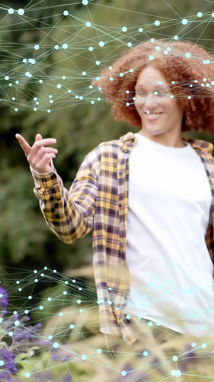 Video verticale: Uomo che esce da fiori viola, camminando, indicando e salutando, mentre i nodi si collegano all'IT