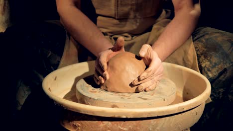 potters hands put clay on a wheel.