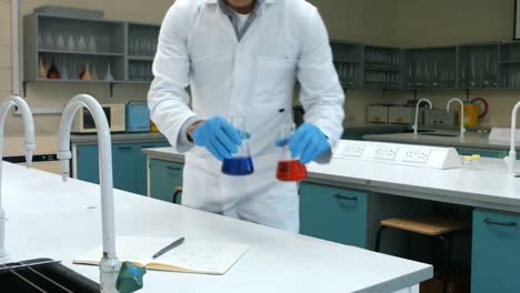 scientist with sample of red and blue chemical writing his notes