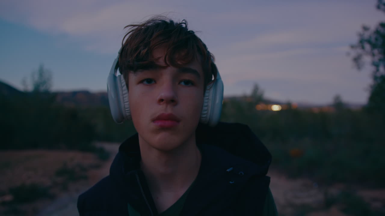 Teenage Boy Listening to Music Outdoors at Sunset