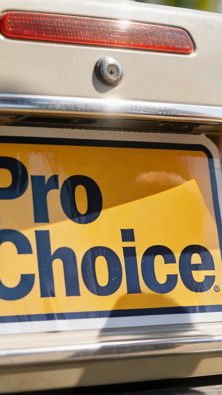 Hand Applying 'Pro Choice' Bumper Sticker to Car