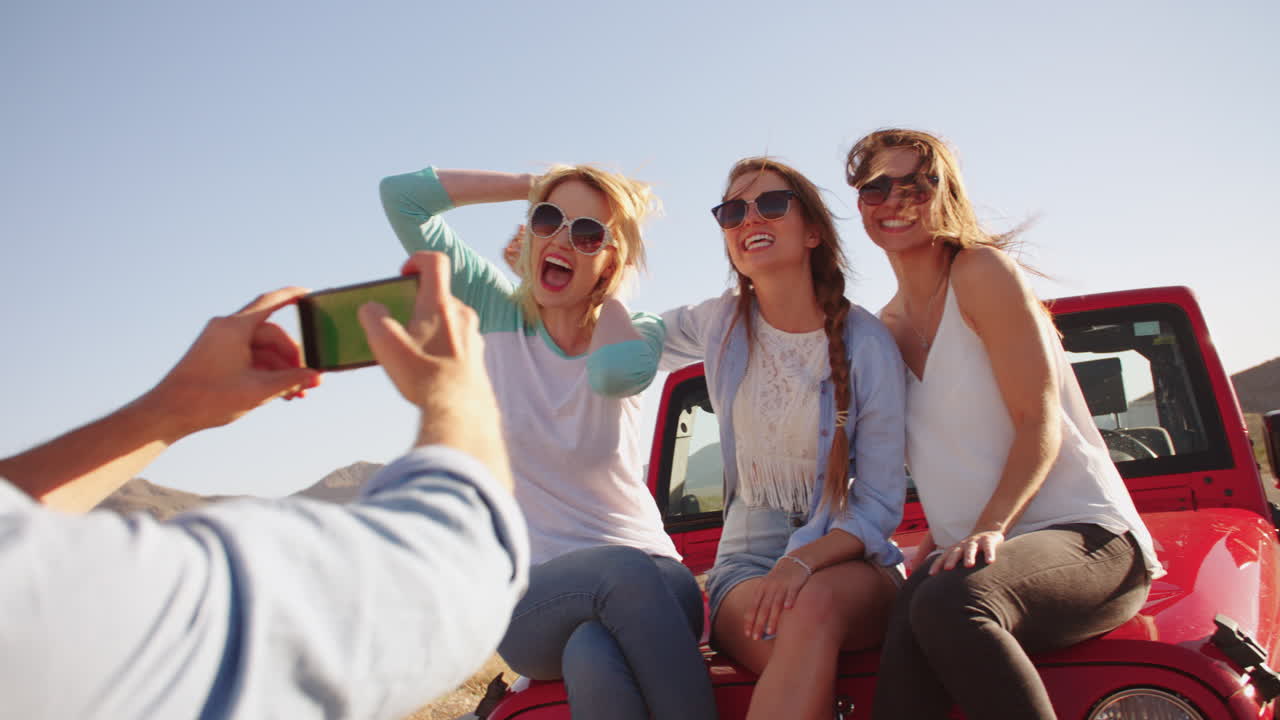 hombre tomando una foto de tres mujeres en un viaje por carretera filmado en r3d