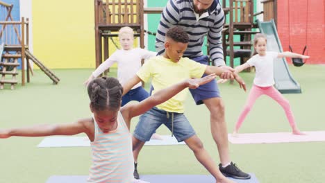 Diverse-male-teacher-and-happy-schoolchildren-exercising-on-mats-at-school-playground