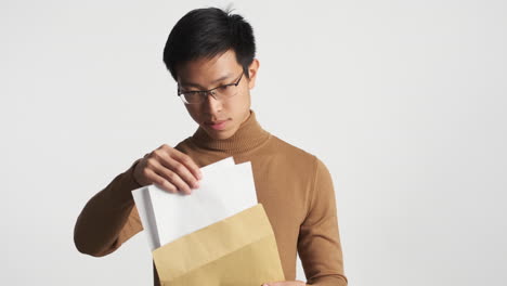 asian man oppening an envelope and reading content.