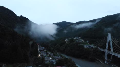 drone aéreo alto sobre valle de niebla espeluznante al atardecer con barranco y puente