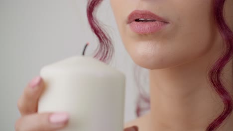 perfect woman lips blowing out candlelight in spa, close up view